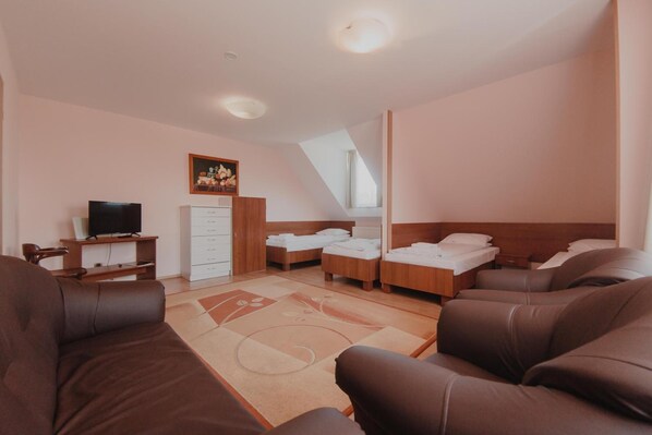 Habitación de hotel con sofá, dos camas, televisor y un cuadro en la pared.