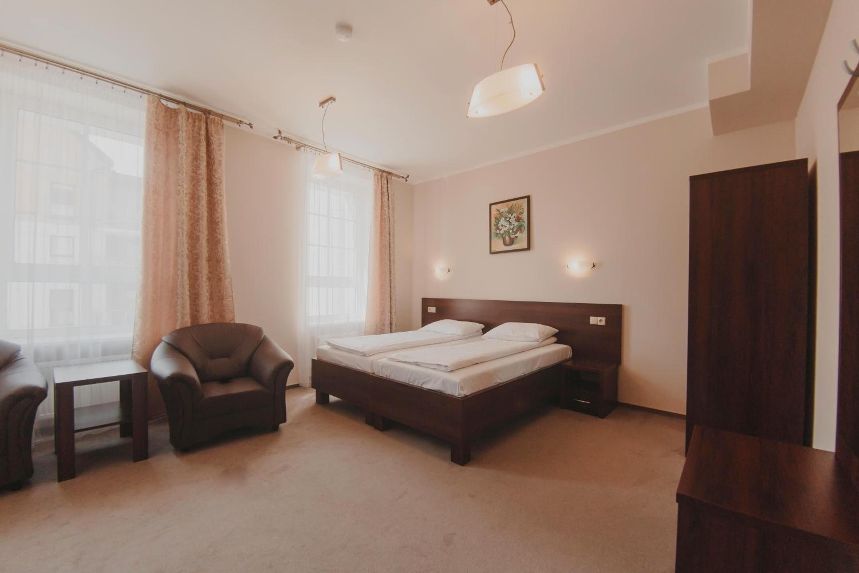 A hotel room with a bed, a chair, a desk, and a wardrobe.