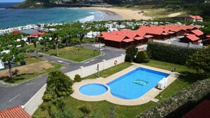 Un resort con una amplia piscina, acceso a la playa y edificios con techos rojos.