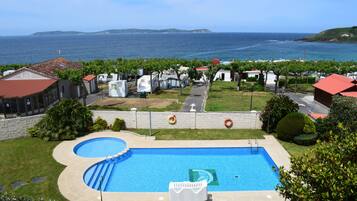 Een buitenzwembad, parasols bij het zwembad en ligstoelen