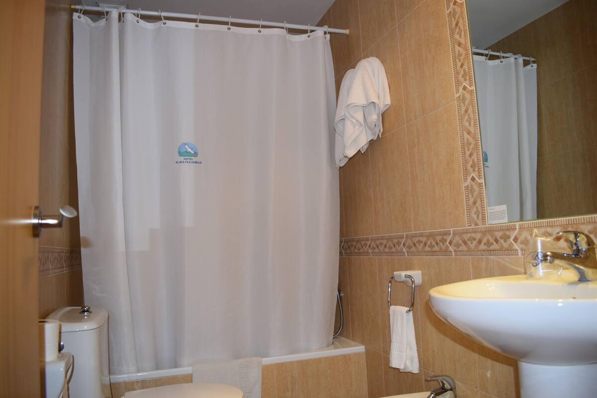 A bathroom with a shower curtain, a sink, and a towel rack.