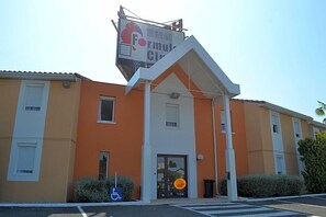 A hotel with a prominent sign, a gated entrance, and a wheelchair-accessible parking space.