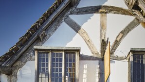 A traditional half-timbered building with a large wooden door, two windows with shutters, and a small balcony. - Sign of the Angel (Chippenham)