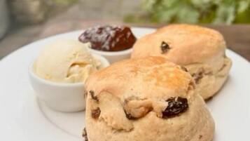 Un piatto con due scones e una piccola ciotola di marmellata.