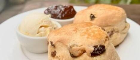 A plate with two scones and a small bowl of jam.