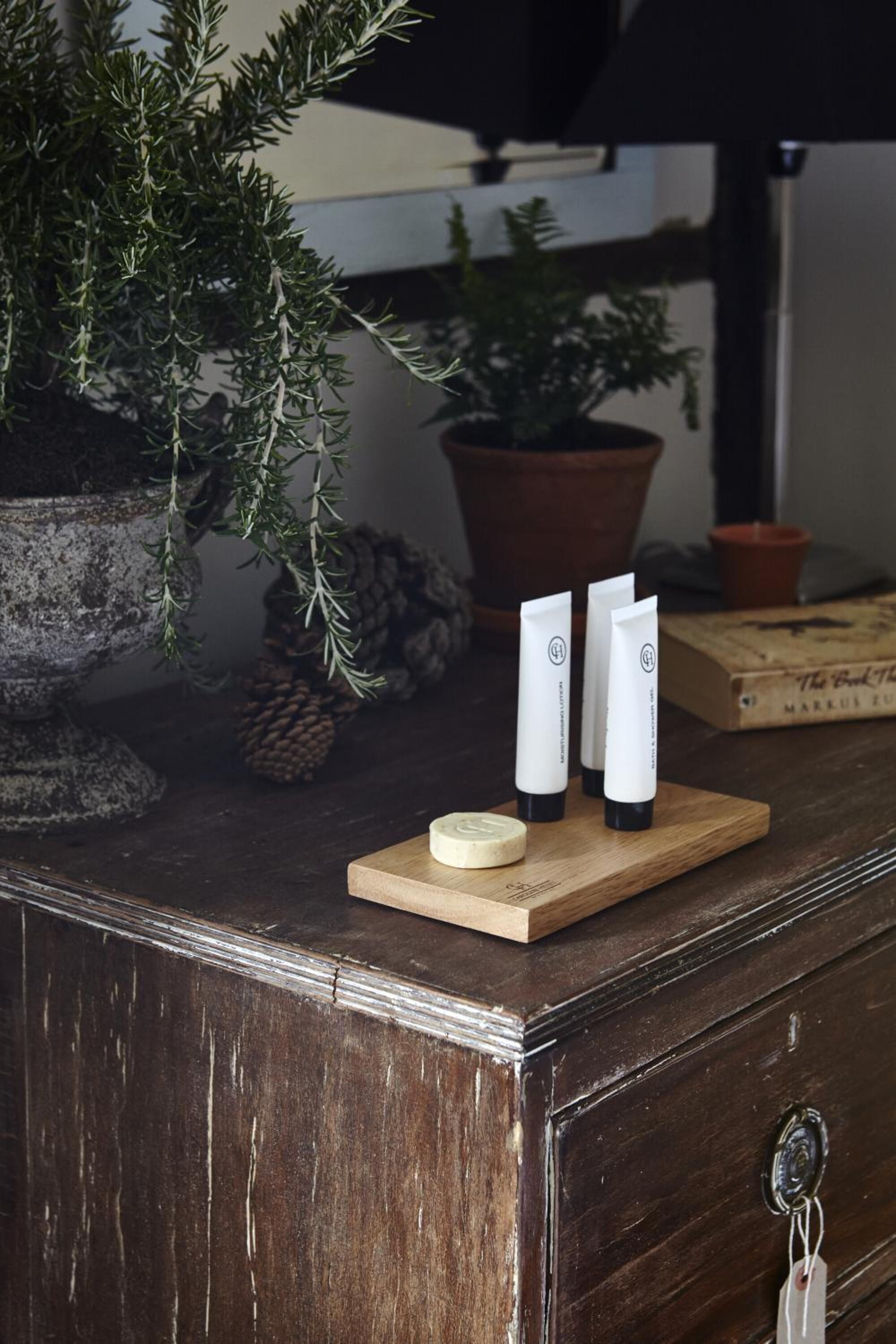 A wooden dresser with a small wooden tray holding three tubes and a round object.