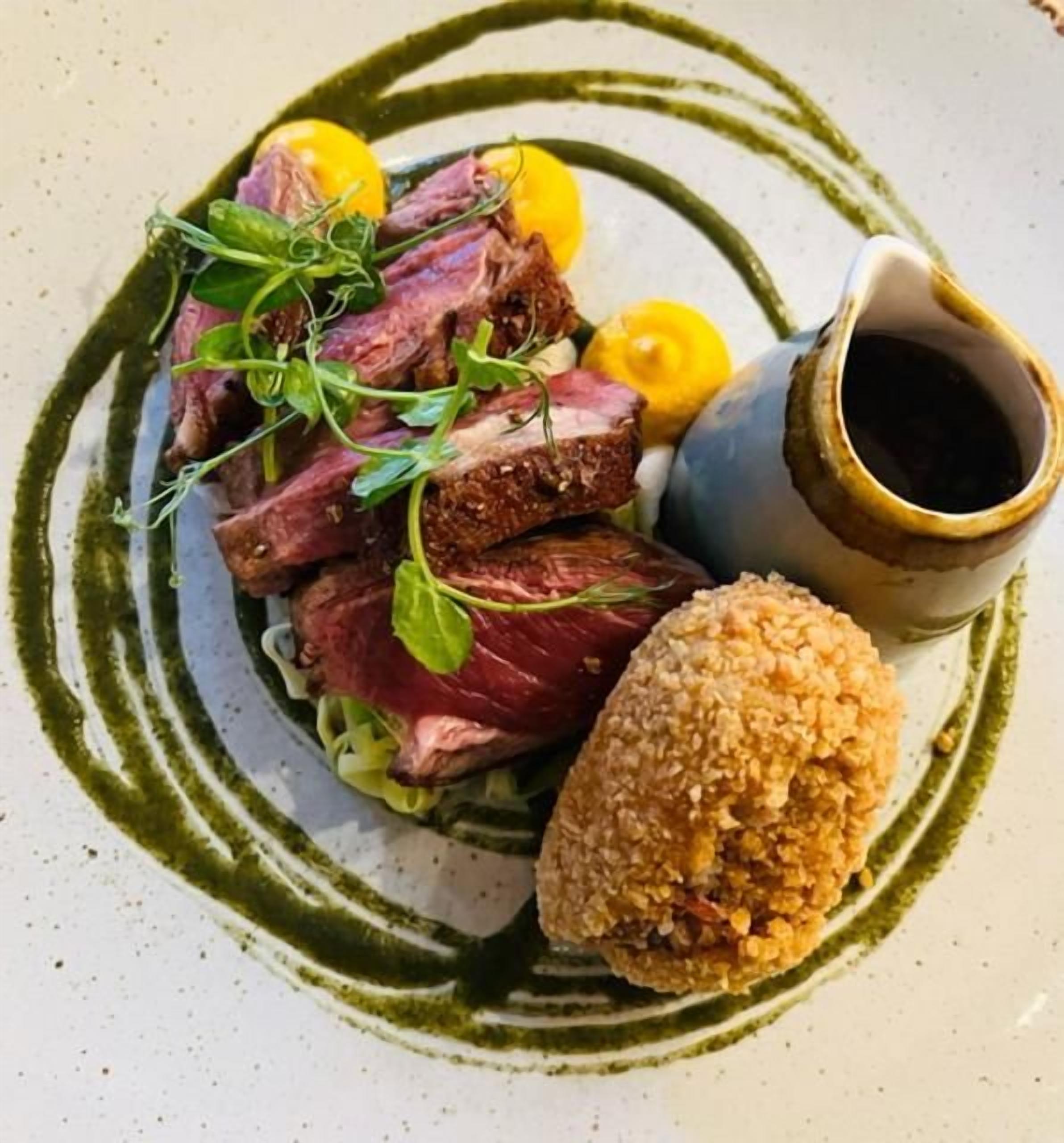 A plated dish with meat, vegetables, and a sauce.