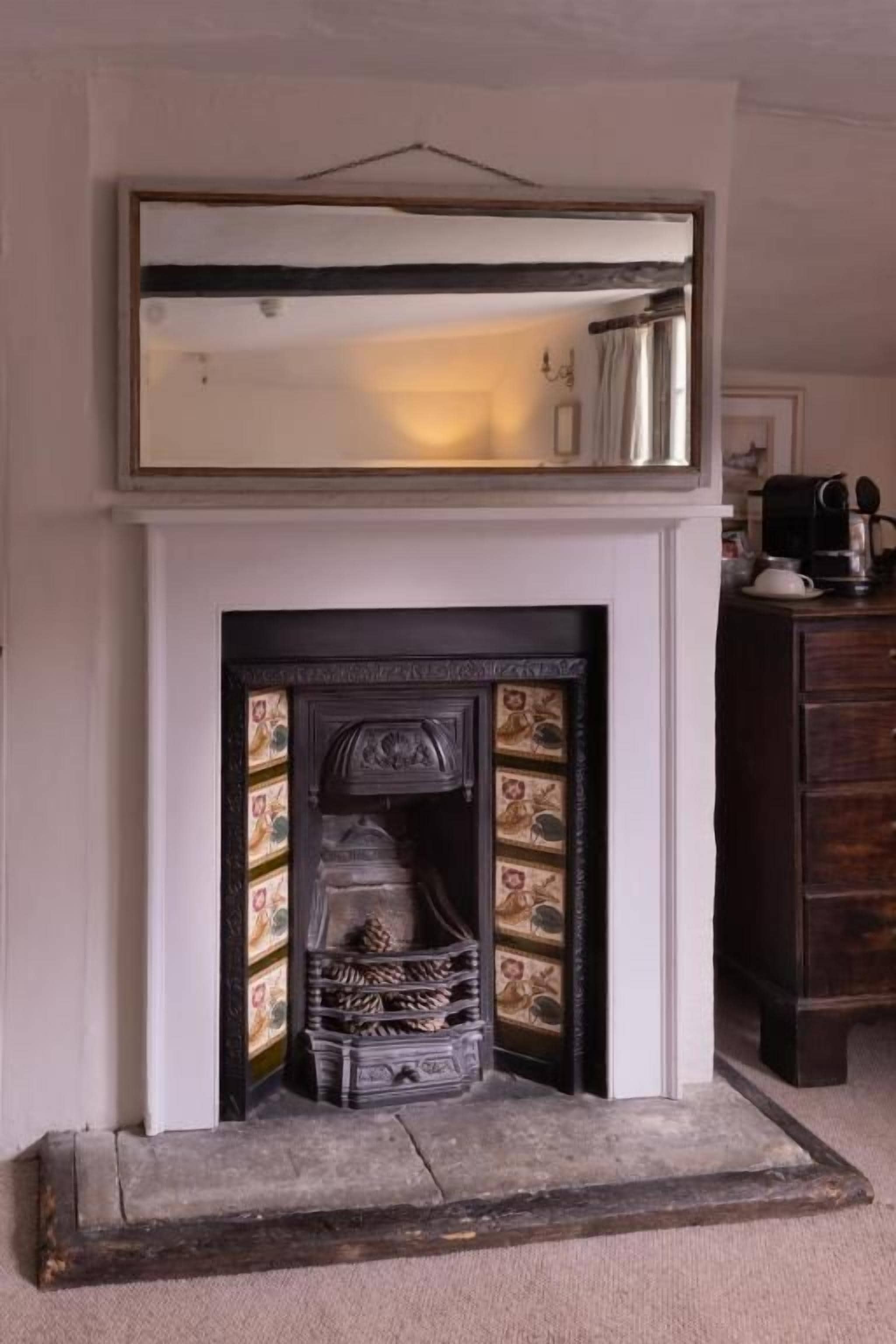 Una chimenea con un manto decorativo y un espejo encima.