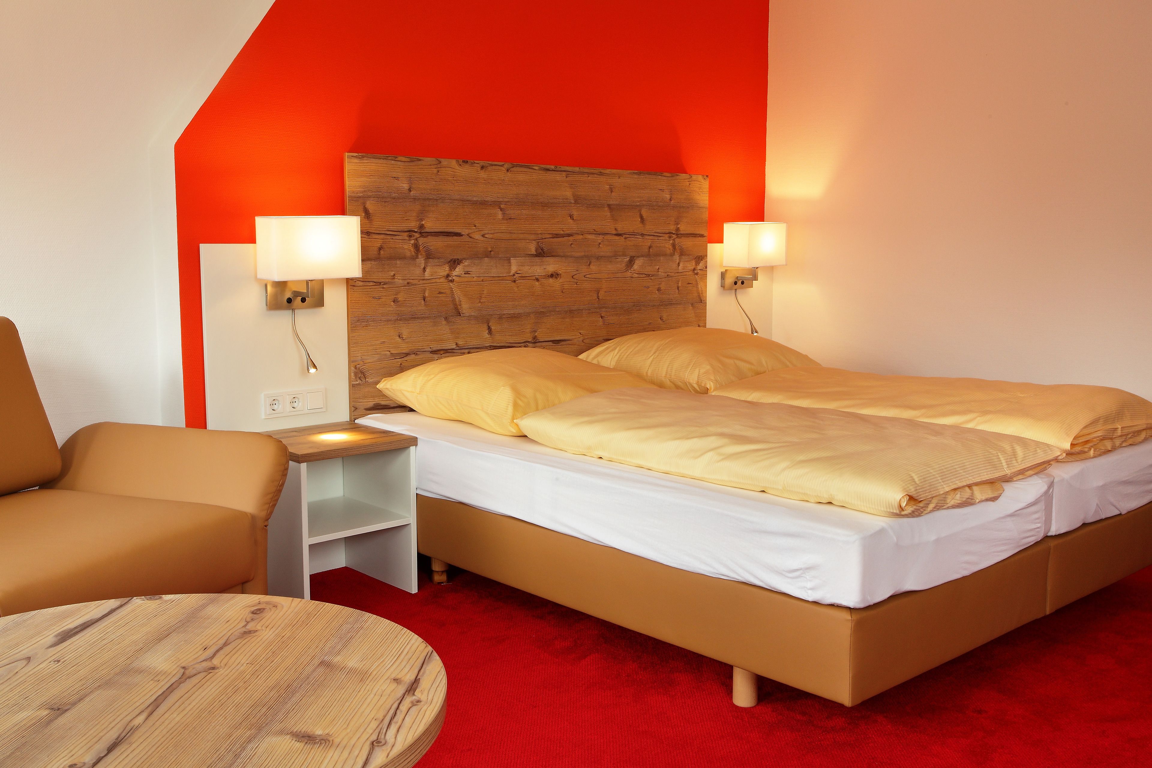 A bedroom with a bed, bedside tables, a chair, and a round table.
