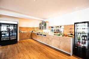 A modern kitchen with wooden cabinets, a central island, and built-in appliances including a refrigerator and a wine cooler.