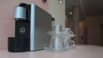 Eine Kaffeemaschine mit Glasbehälter und mehreren Tassen auf einer Arbeitsplatte.