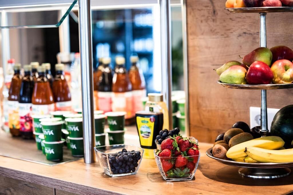 A display of various fruits and beverages, including apples, bananas, strawberries, blueberries, and bottles of juice.