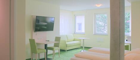 A room with a bed, a desk, a chair, a television, and a window.