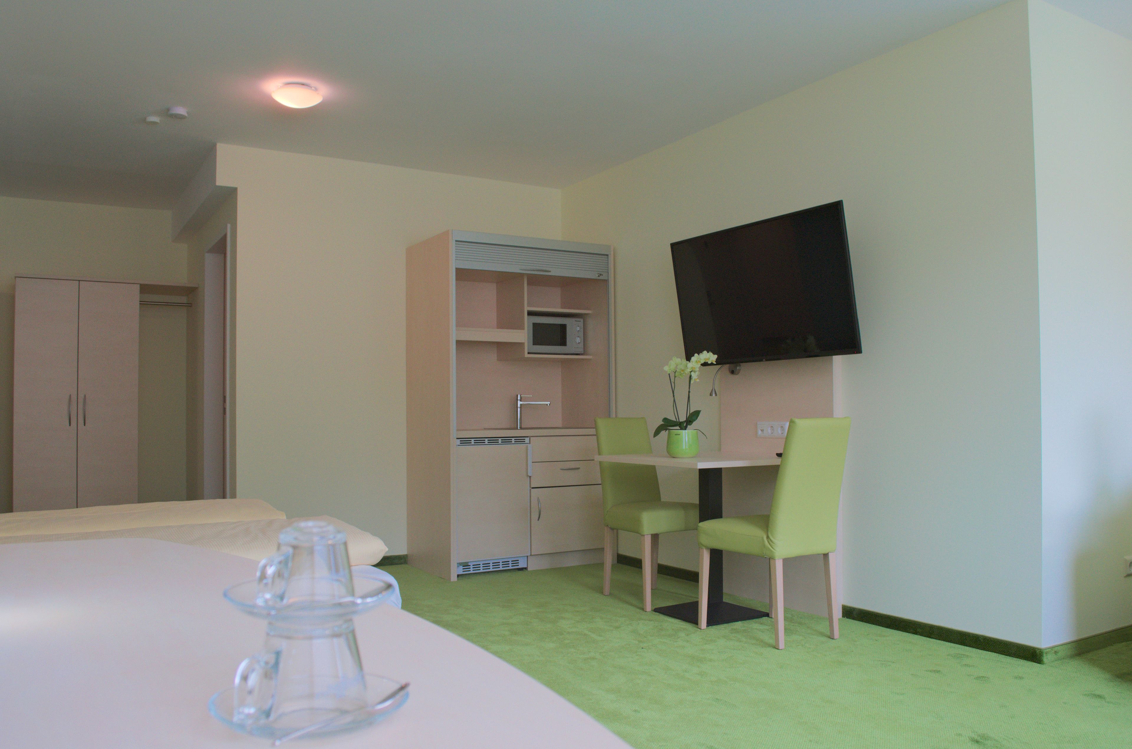 Una habitación de hotel con cama, escritorio con silla, microondas, televisor y armario.