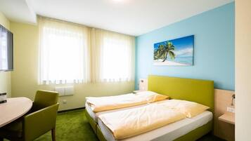 A hotel room with two single beds, a desk, a chair, a painting of a beach, and a window with curtains.
