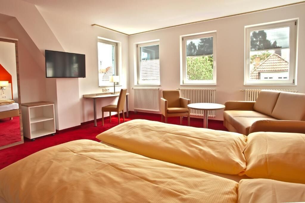 Un dormitorio con cama, escritorio, silla, sofá y televisor.