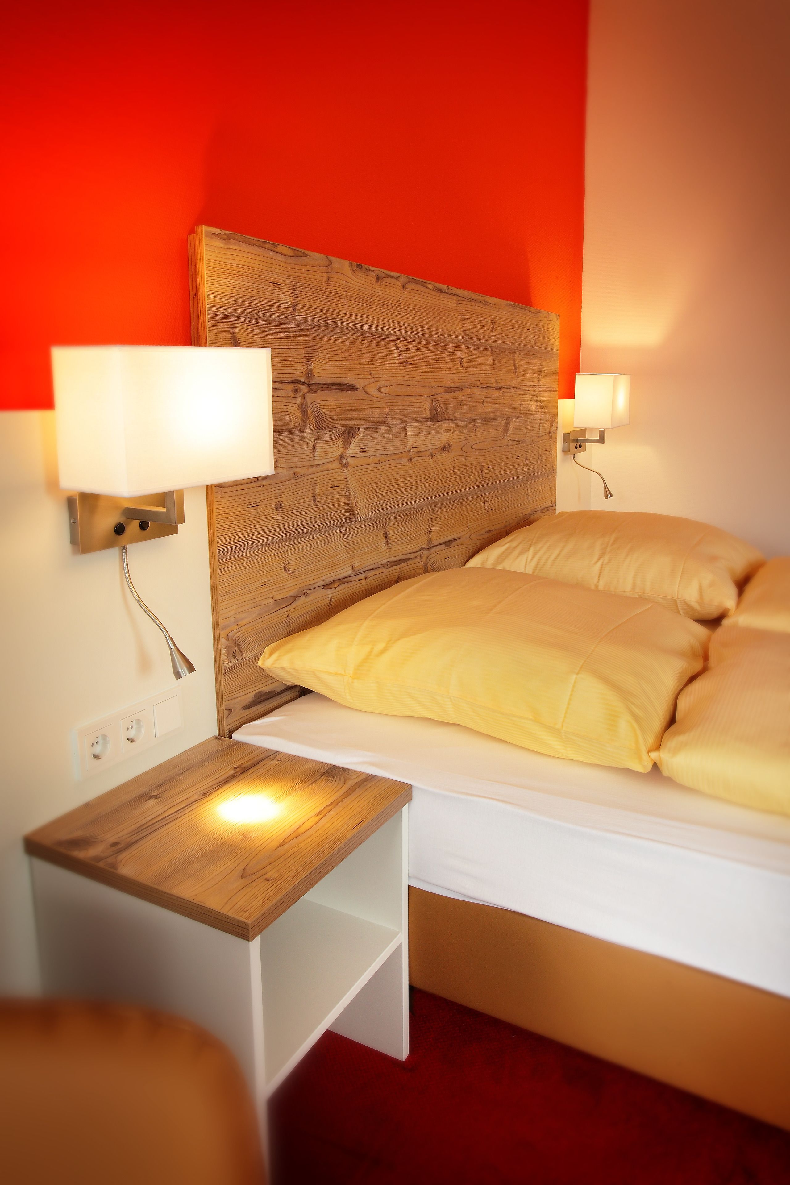 A bed with a wooden headboard, two bedside lamps, and a nightstand with a lamp.