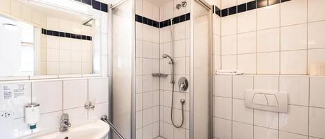 A modern bathroom with a glass-enclosed shower, a sink with a mirror, and a toilet.