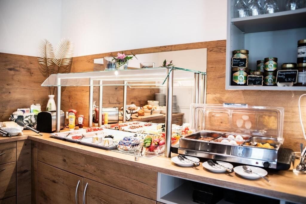 A buffet setup with various food items and condiments, a glass display case, and a shelf with jars.