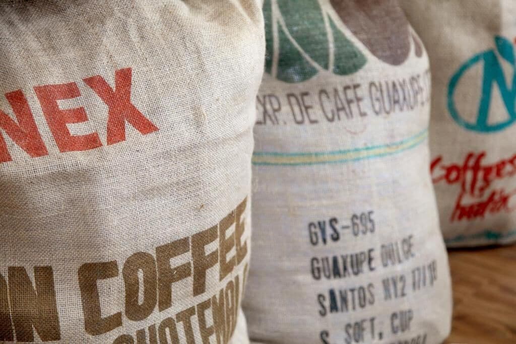 Kaffeebeutel aus Jute mit Aufschrift, die auf ein Café hinweist.