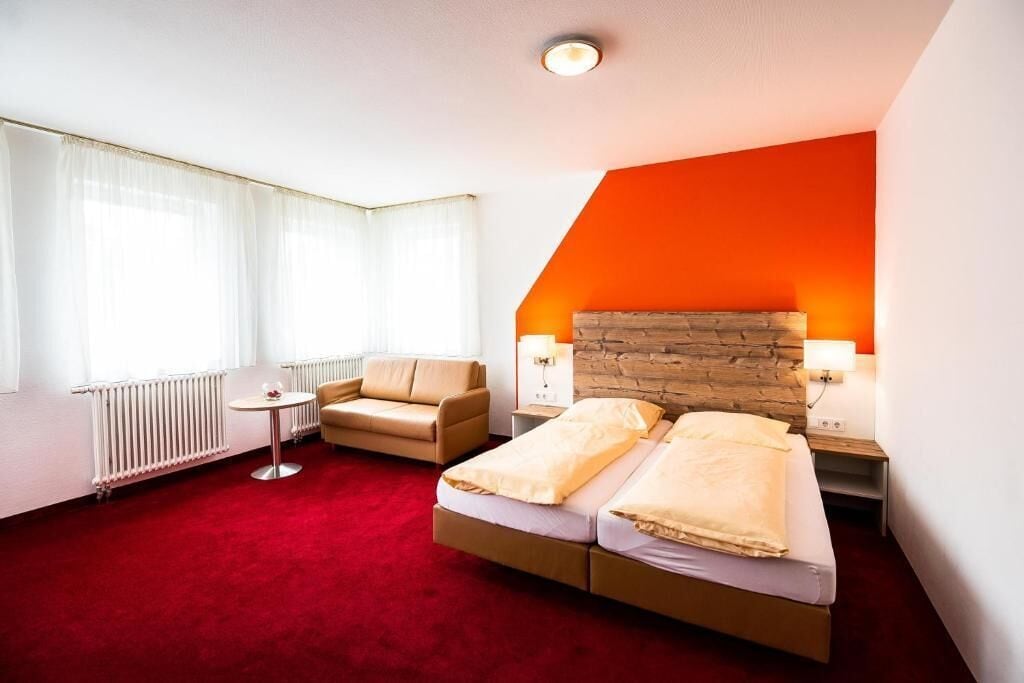 Una habitación de hotel con cama, una silla, una mesita y un radiador.