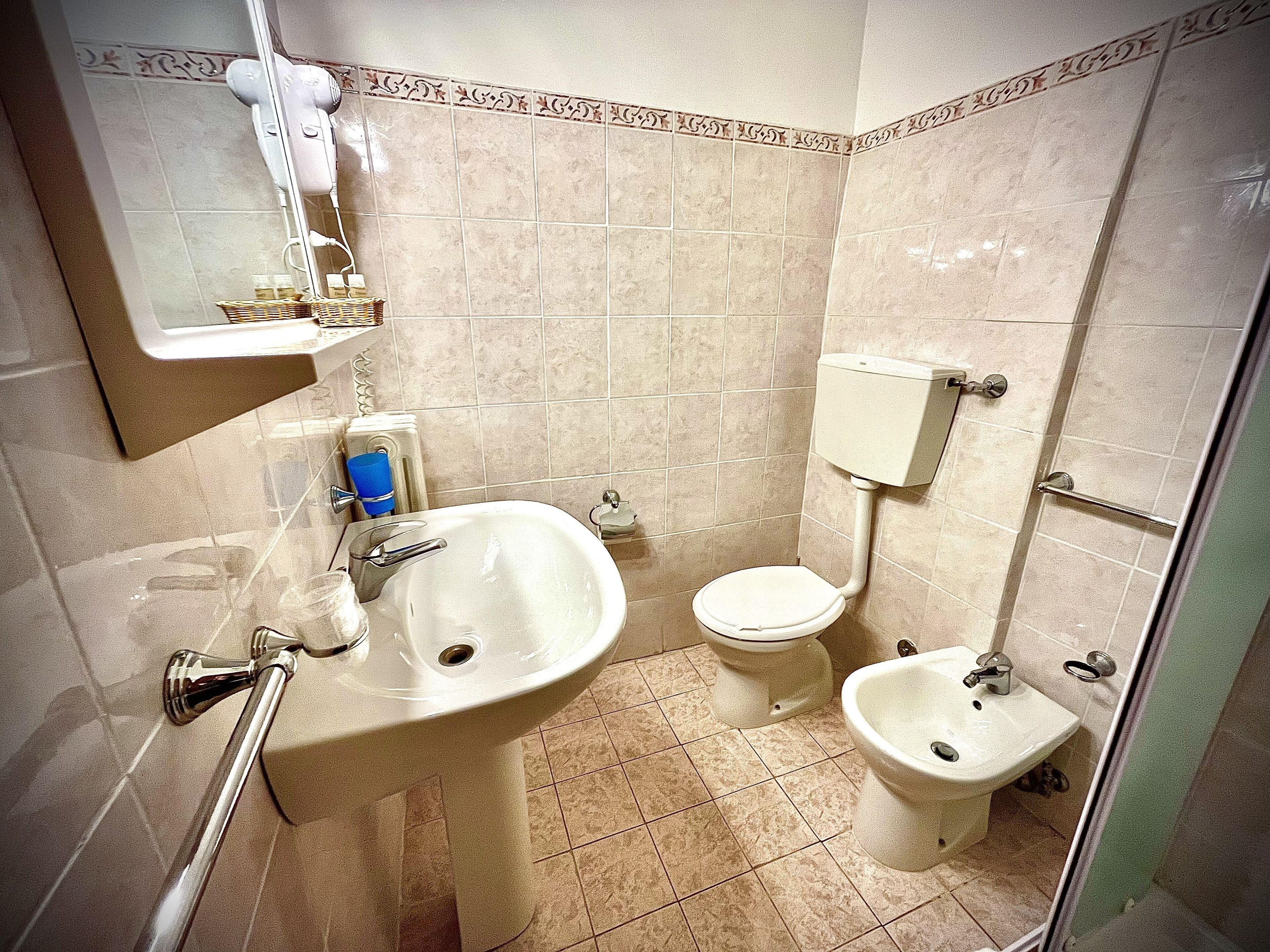 Un baño con lavabo, inodoro, bidé y un espejo con secador de pelo.