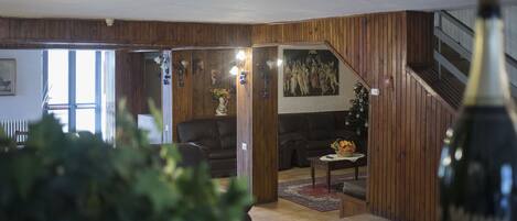 Una sala de estar con paneles de madera, un sofá, una mesa de centro y un árbol de Navidad.