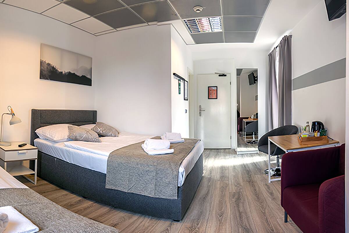 Una habitación de hotel moderna con una cama grande, un escritorio con silla, una lámpara de escritorio y un cuadro en la pared.