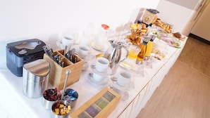 Un aparador de buffet amb diferents plats, utensilis i una màquina de cafè.