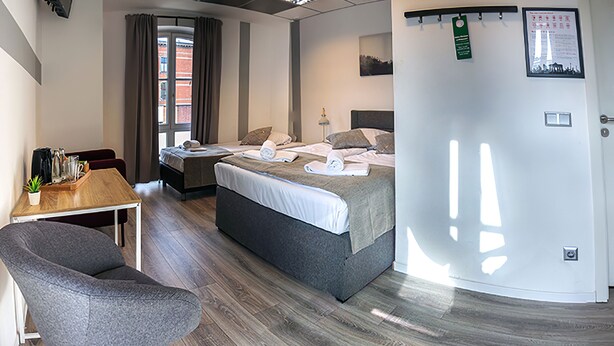 Habitació d'hotel amb dos llits, un escriptori, una cadira i vista a l'exterior.
