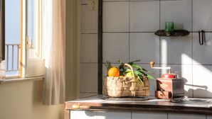 A kitchen counter with a woven basket containing fruits and a red appliance. - Casa Nannina (Meta)