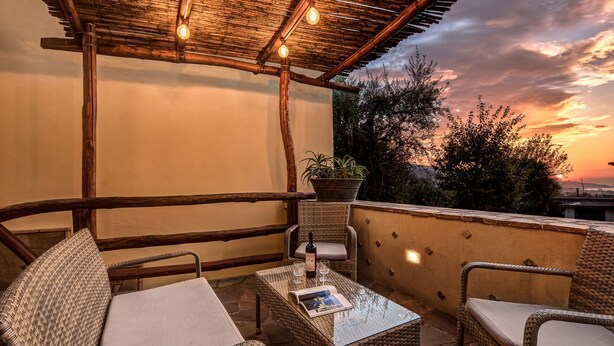 A balcony with wicker furniture, a table with a bottle and glasses, and a potted plant. - Casa Nannina (Meta)