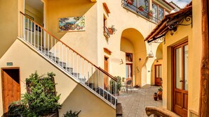 A courtyard with a staircase leading to an upper floor, potted plants, and a wooden bench. - Casa Nannina (Meta)