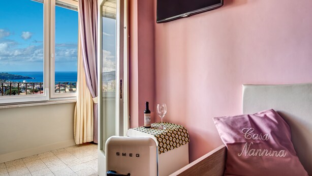 A room with a view of the sea, a minibar, a TV, and a bed with a pillow. - Casa Nannina (Meta)