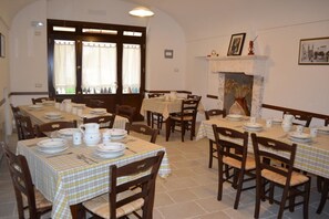 A dining area with multiple tables set for meals, featuring checkered tablecloths and wooden chairs. - Coppola di Seta (Locorotondo)