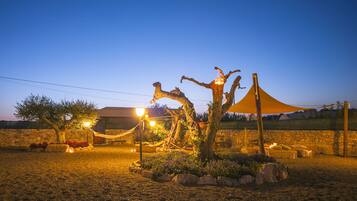 Un espacio al aire libre bien iluminado con una hamaca, un árbol y una tienda de campaña.