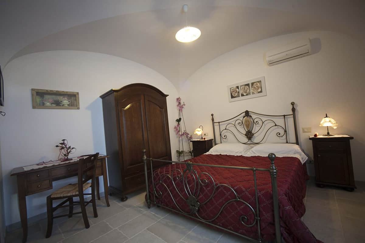 A bedroom with a bed, a desk, and a chair.
