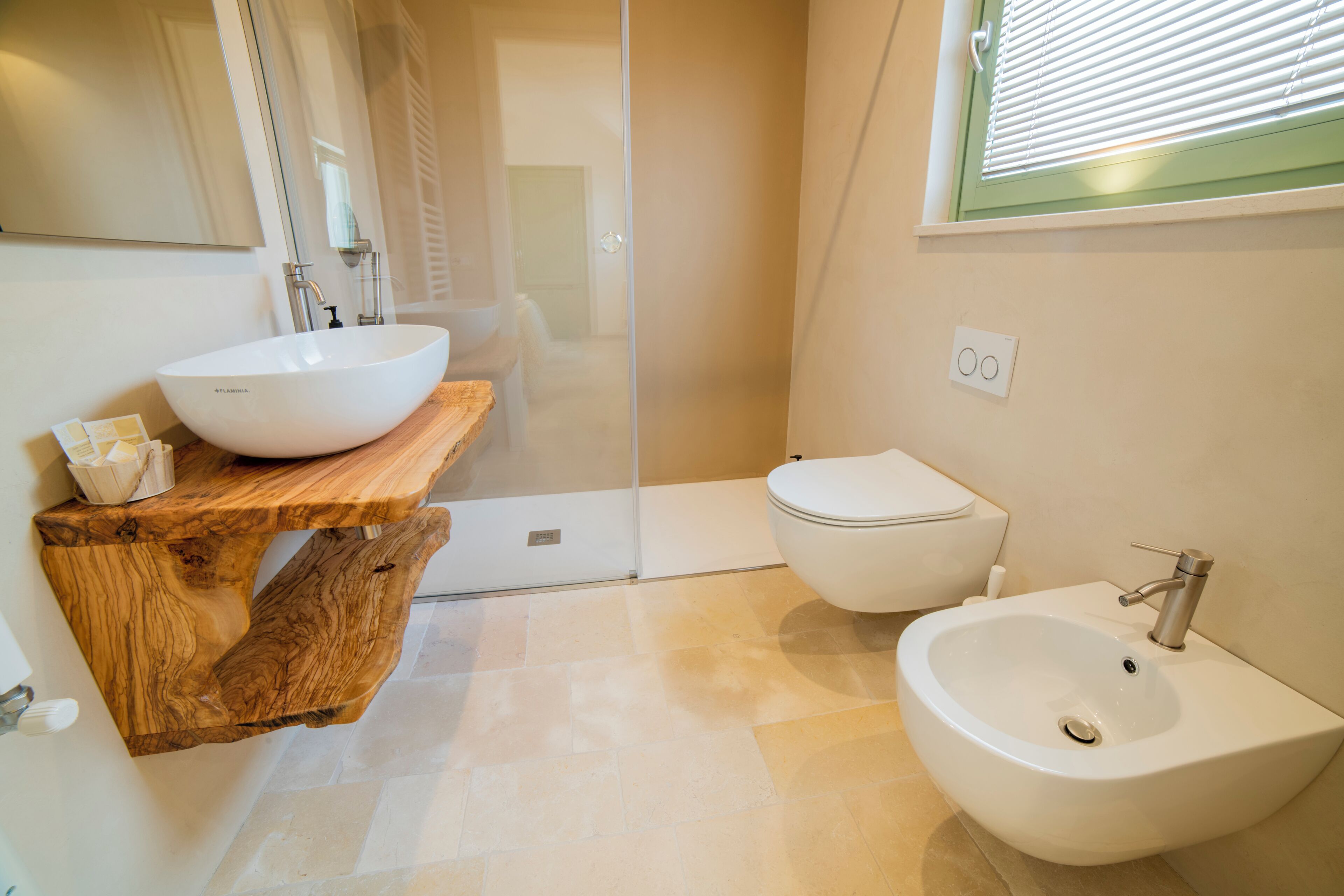 A bathroom with a wooden vanity, a white sink, a toilet, and a shower area.