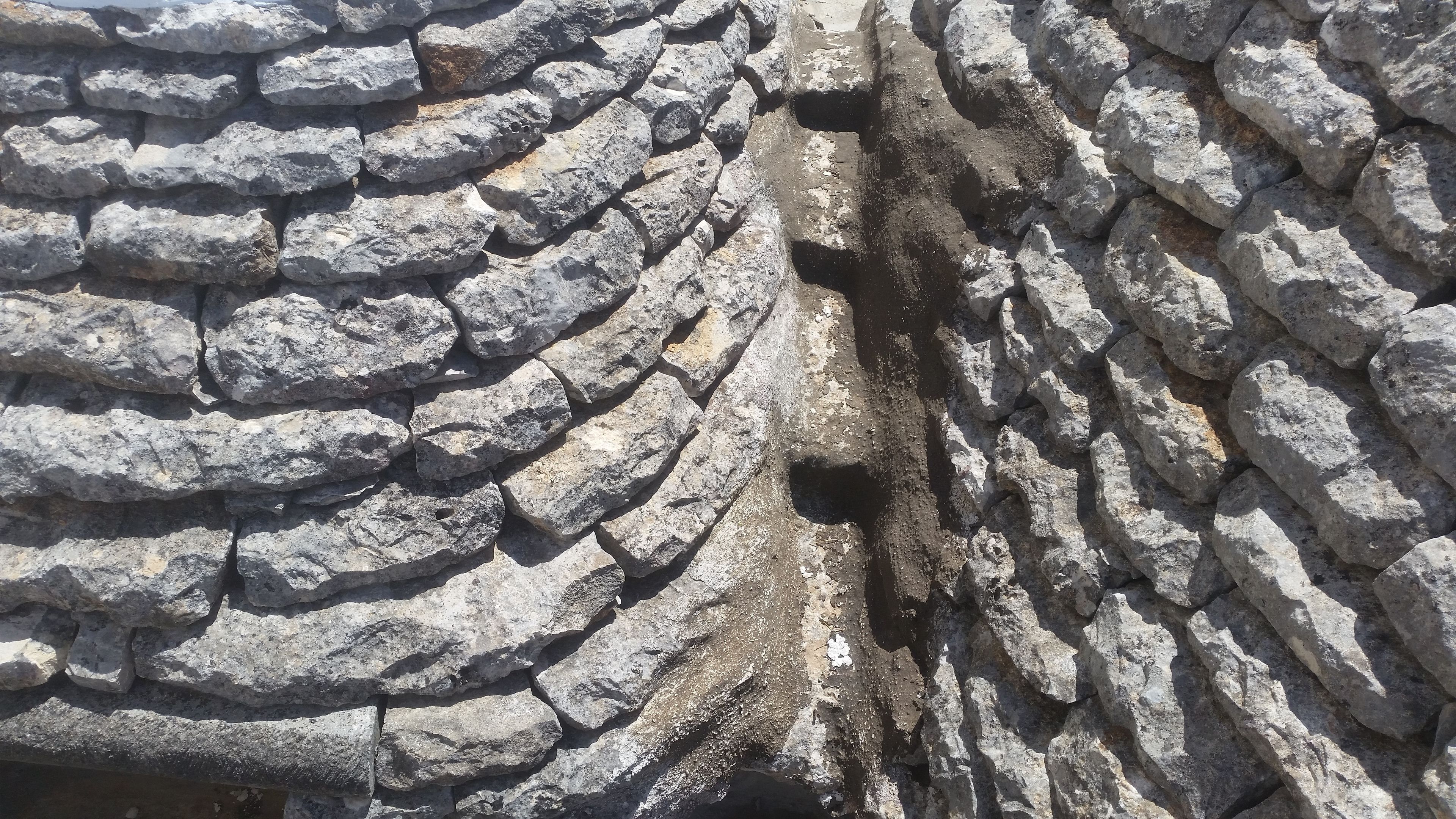 A stone wall with a rough texture and irregular shapes.