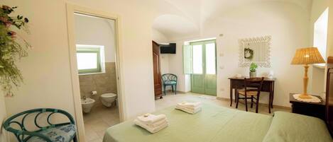 A hotel room with a bed, a desk, a chair, a television, and a bathroom.