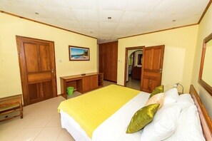 Un dormitorio con cama, armario de madera, escritorio y un cuadro en la pared.