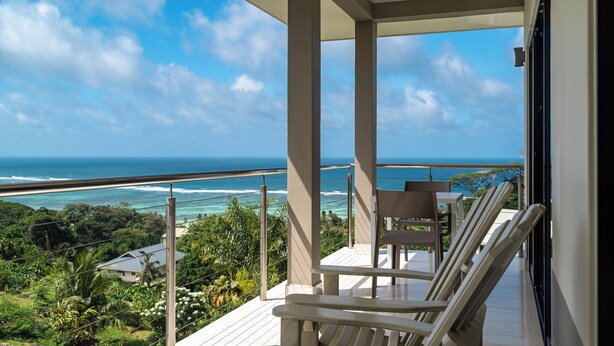 Un balcon avec vue sur l’océan, une table et deux chaises.