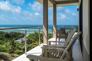 Un balcon avec vue sur l’océan, une table et deux chaises.