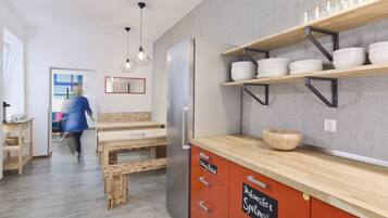 A modern kitchen with wooden cabinetry, a built-in refrigerator, and a wooden dining table.