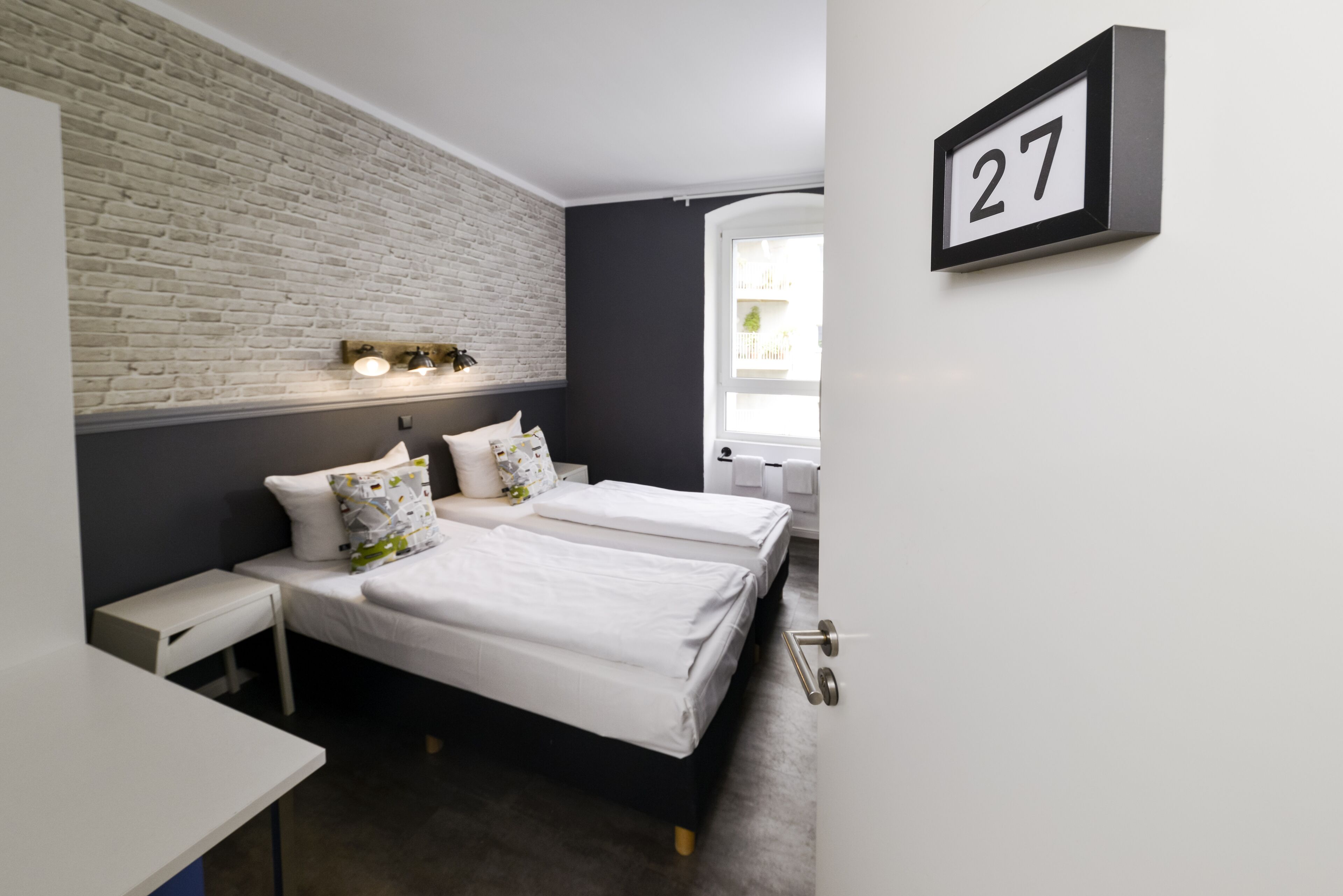Ein modernes Schlafzimmer mit zwei Betten, einer Ziegelwand, einem Nummernschild und einem Fenster.
