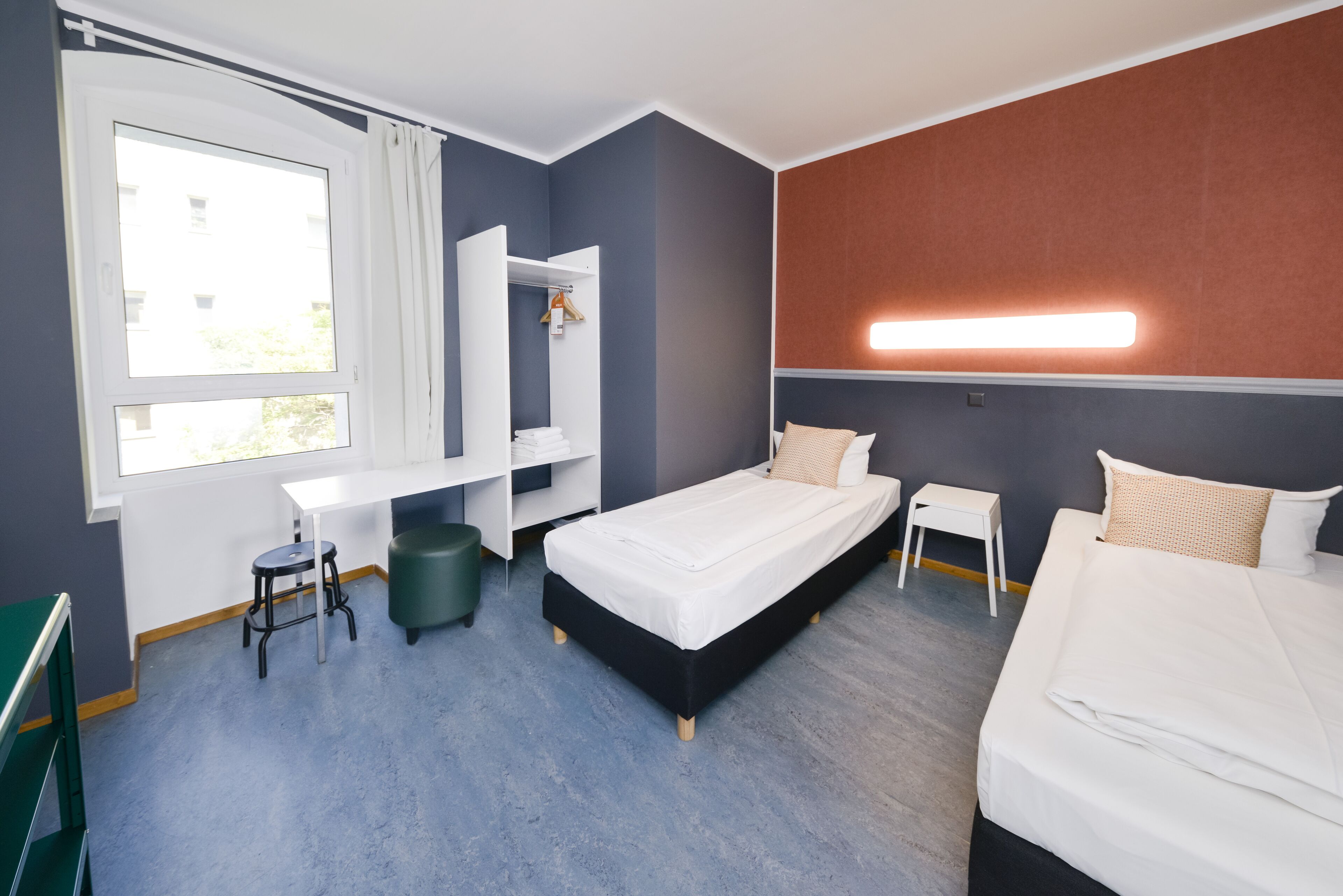 Ett modernt hotellrum med en säng, ett skrivbord och en stol.