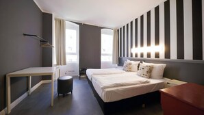 Una habitación de hotel moderna con cama, escritorio, silla y una mesita.