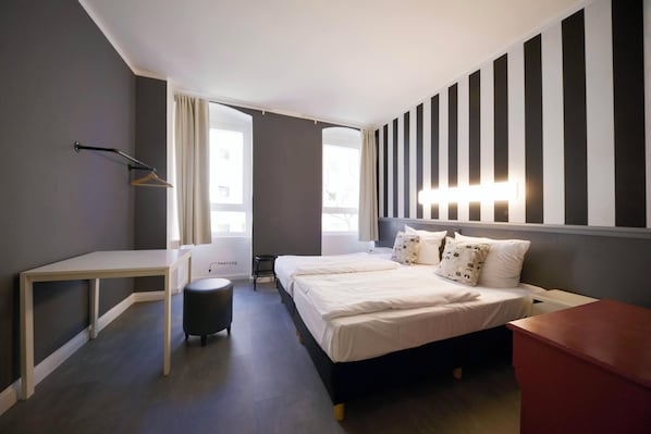 Una habitación de hotel moderna con cama, escritorio, silla y una mesita.