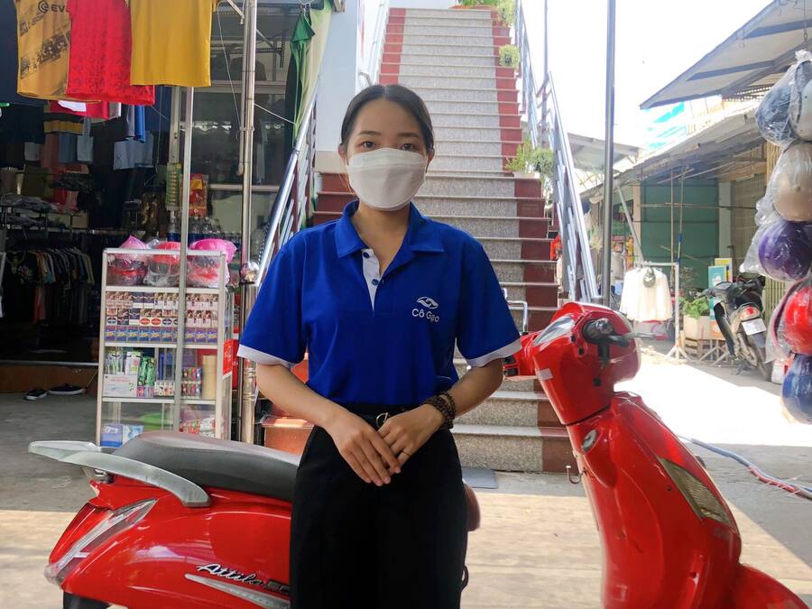 A person standing next to a red scooter in front of a hotel sign.