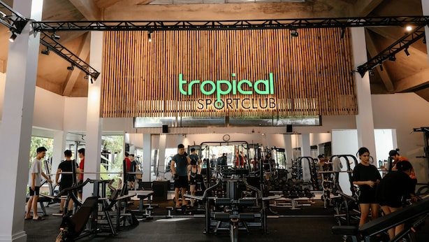 Un gimnasio con diversos equipos de ejercicio y un cartel que dice "tropical sportclub".